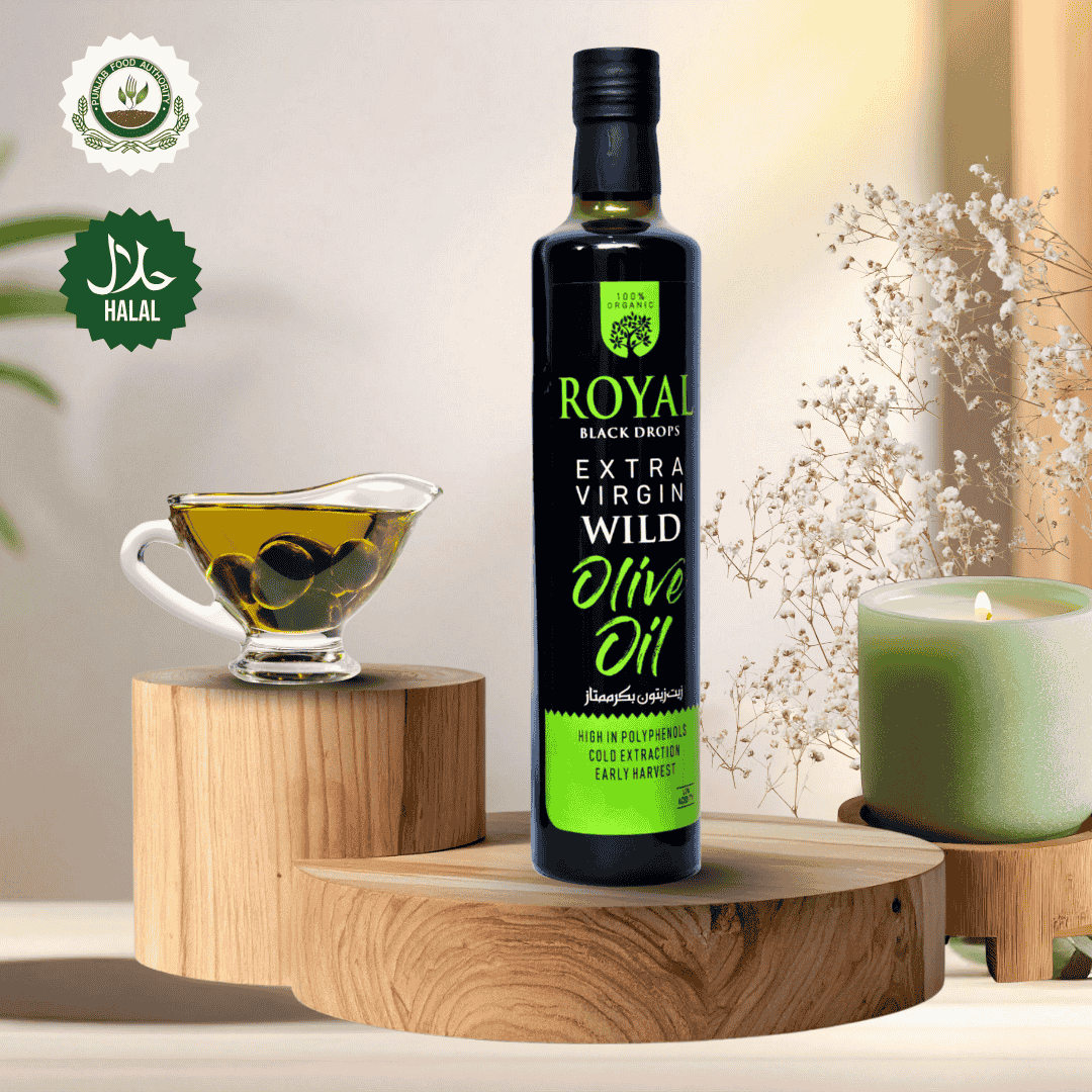 Bottle of Royal Black Drops Extra Virgin Wild Olive Oil on a wooden stand with a cup of olives and candle in the background.