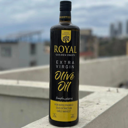 Bottle of Royal Golden Drops Extra Virgin Olive Oil on a rooftop with a blurred cityscape background
