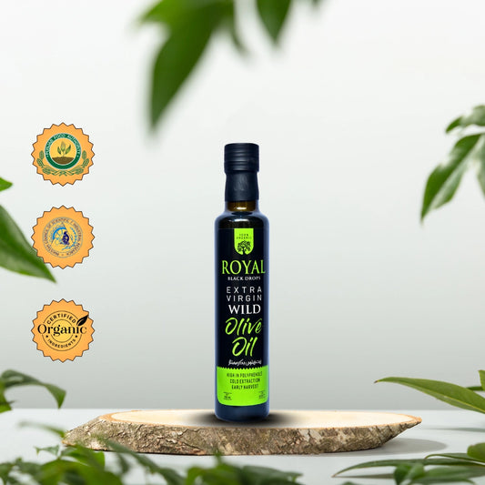 Bottle of Royal Extra Virgin Wild Olive Oil on a wooden board with green leaves in the background